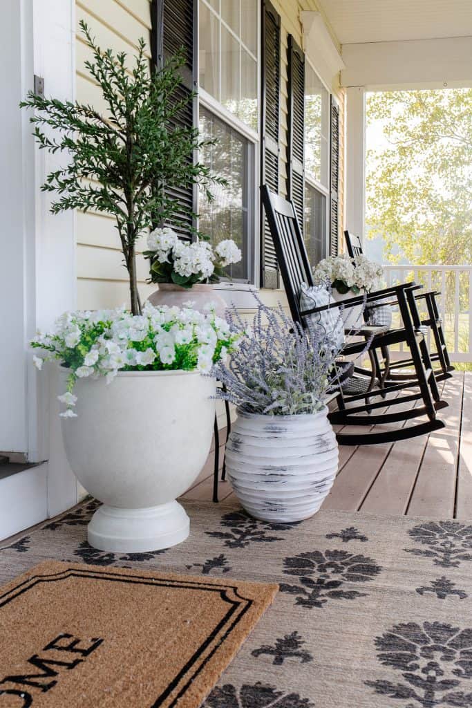 front porch with planters and rug